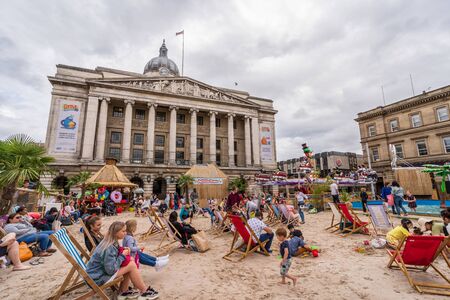 NOTTINGHAM, UK - AUGUST 07, 2019: Council House (City Hall) at Old Market Square with a pool, fountain, sand and beach chairs in the foreground.のeditorial素材