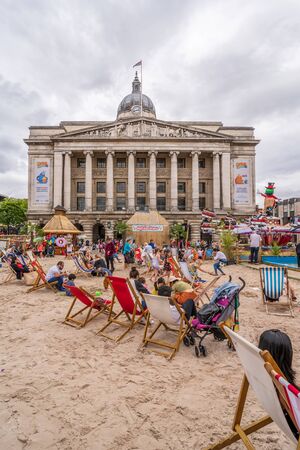 NOTTINGHAM, UK - AUGUST 07, 2019: Council House (City Hall) at Old Market Square with a pool, fountain, sand and beach chairs in the foreground.のeditorial素材