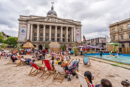 NOTTINGHAM, UK - AUGUST 07, 2019: Council House (City Hall) at Old Market Square with a pool, fountain, sand and beach chairs in the foreground.のeditorial素材