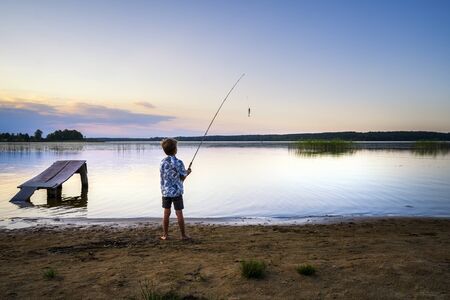 RIGA, LATVIA - AUGUST 16, 2019: Young Latvian boy fishing in Juglas lake at sunset, Latvian nature, Riga, Latvia, Europeのeditorial素材