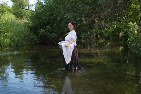 peasant woman washes clothes in the river near the forest