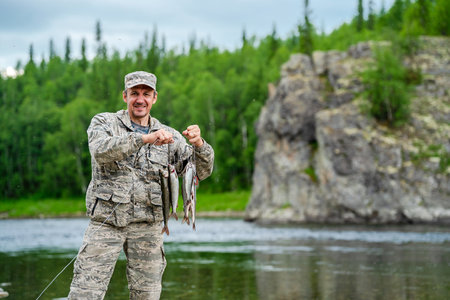 Fisherman with his catch of fish against the backdrop of a rock