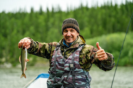 A male fisherman holds a fish he caughtの写真素材