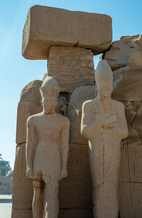 Two Egyptian statues near large blocksの写真素材