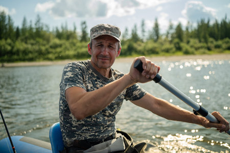 An elderly fisherman rows with an oar and looks aheadの写真素材