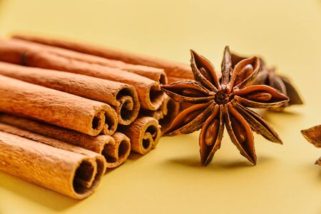 Close-up of spices: cinnamon sticks and star anise on a yellow background.の写真素材