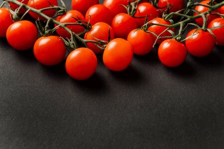 Cherry tomatoes lie on a dark textured background with space for text.の写真素材