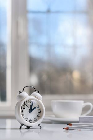 composition with an alarm clock, a notebook, pencils and a cup of coffee on the table. Business morning concept.の写真素材