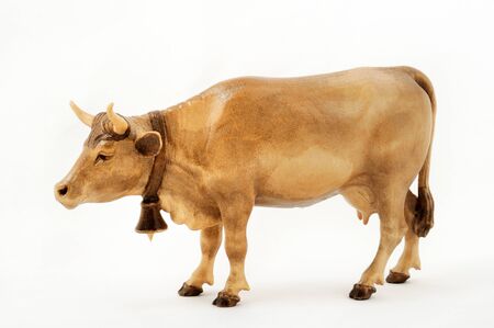 Wooden figurine of a cow with a bell on his neck isolated on a white background.の写真素材