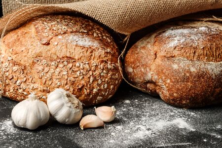 The concept of a rural bakery. Coarse rustic bread closeup on a table sprinkled with flour.の写真素材