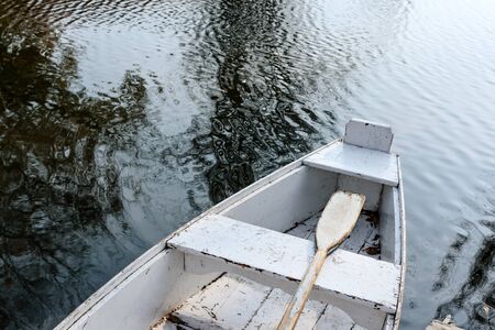 Old rowing boat of white color on a background of water. The concept of outdoor recreation.