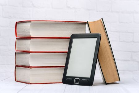 A stack of paper books and an electronic book on a white background. The concept of modern...