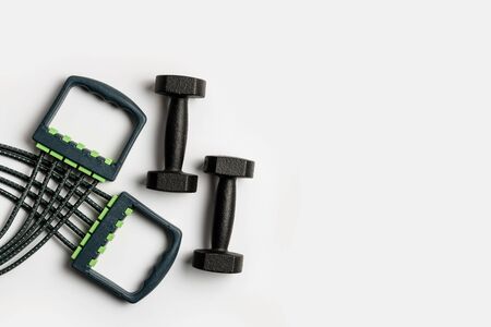 Expander and two dumbbells isolated on a white background. Sport lifestyle concept with place for text.の写真素材