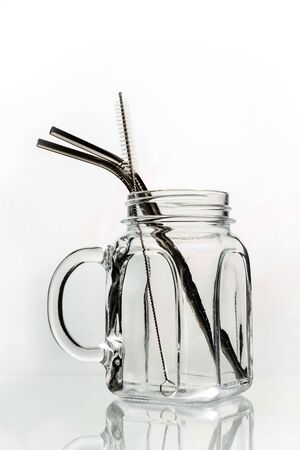Glass jar for smoothies and cocktails with a set of metal cocktail tubes on a white background.の写真素材