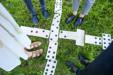 Huge wooden dominoes and players legs on the grass. View from above. Outdoor entertainment concept.の写真素材