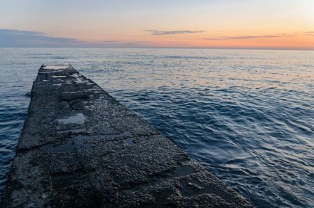 Concrete pier leaving the sea on a sunset background. Sea vacation concept.の写真素材