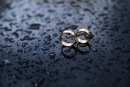 Two wedding rings on a smooth surface with water drops. Wedding concept with selective focus.の写真素材