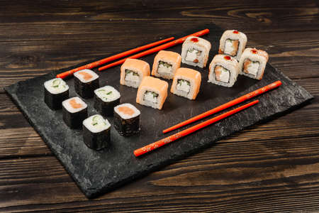 set of japanese rolls on a stone dish with chopsticks.の写真素材
