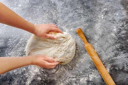 Female hands knead the dough. The concept of home cooking. Flat lay composition with dough in female...