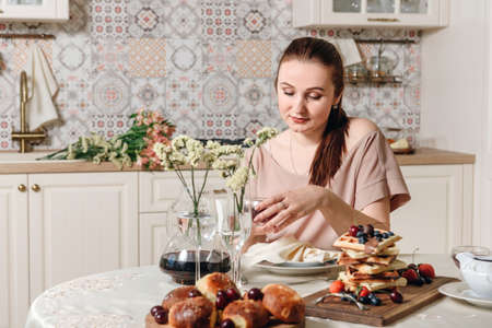 Young woman at the table with cooked breakfast. The concept of a cozy home.の写真素材