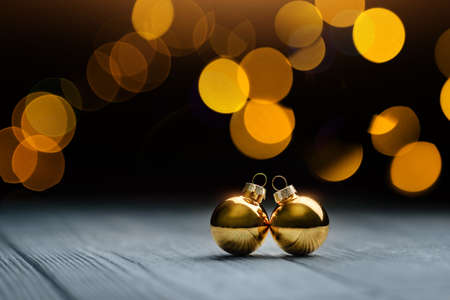 Two Christmas balls lie on the table against the background of garland lights. Christmas and New Year concept.の写真素材