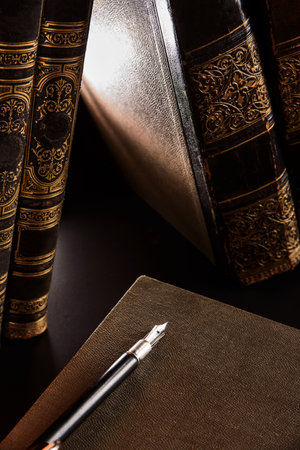 Vintage fountain pen and antique books on darkの写真素材