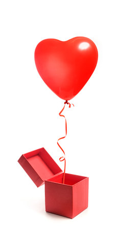 A heart-shaped balloon flies out of an open gift box. Box and balloon isolated on white background. Valentine's Day gift.の写真素材