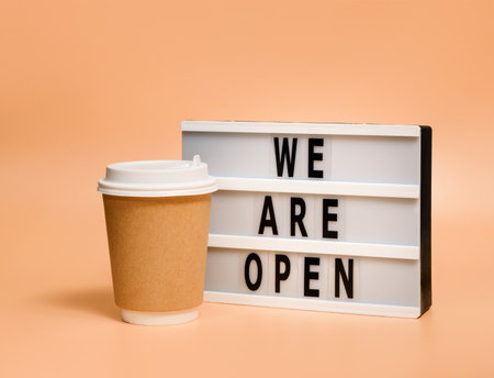 Disposable beverage cup and lightbox with the words "We are open" on a pastel background with copy space.の写真素材