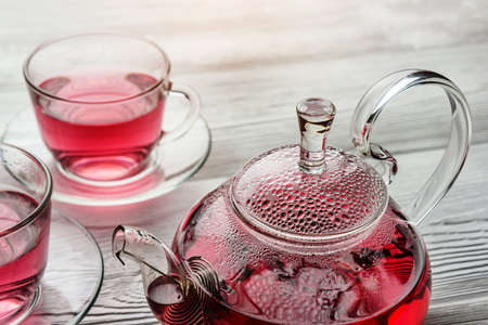 Misted teapot and cups of tea close-up. Hibiscus tea in a glass teapot.の写真素材