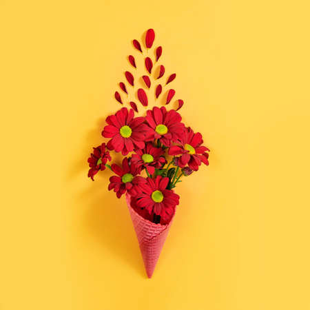 Red flowers on a yellow background. A bouquet of chrysanthemums in a waffle cup. Valentine's day concept.の写真素材