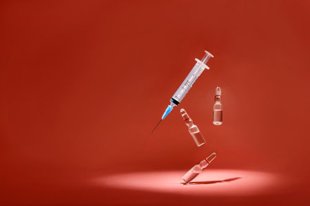 Syringe and ampoules with medicine levitate on a red background with copy space.の写真素材