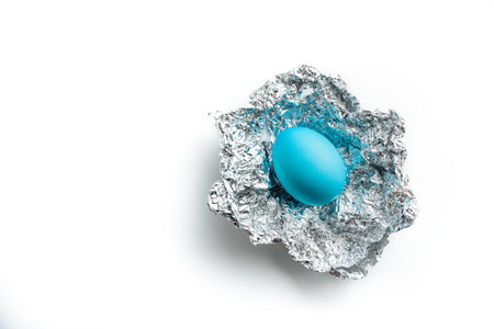 Easter egg in silver foil on a white background with copy space. Easter gift concept.の写真素材