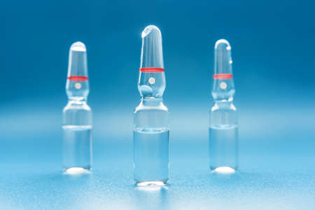 Three ampoules with medicine close-up on a blue background.の写真素材