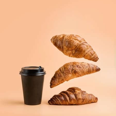 A glass for hot drinks and three croissants on a pastel background. Coffee and croissants. Light breakfast.の写真素材