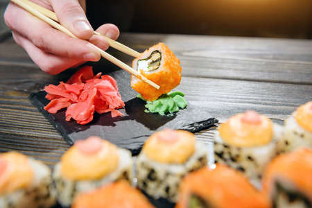 fish roll held with chopsticks close-up. Roll hiccup in wasabi.の写真素材