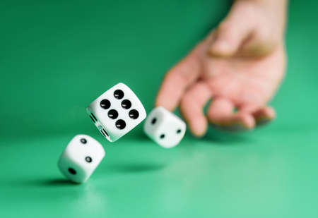 Hand throws dice on a green background with selective focus. Dice close up.の写真素材