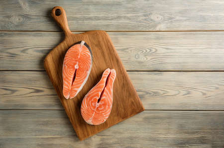 Two salmon steaks on a cutting board. Composition with salmon steaks on the background of a wooden table with copy space.の写真素材