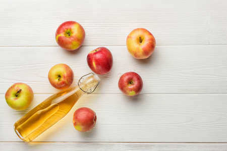 A bottle of apple juice and a few apples on the background of white boards with copy space. Flat lay...