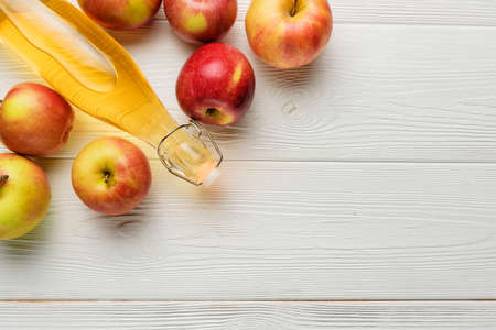 A bottle of apple cider vinegar or juice with apples on a white background with copy space. Flat lay composition with apple cider in a glass bottle close-up.の写真素材