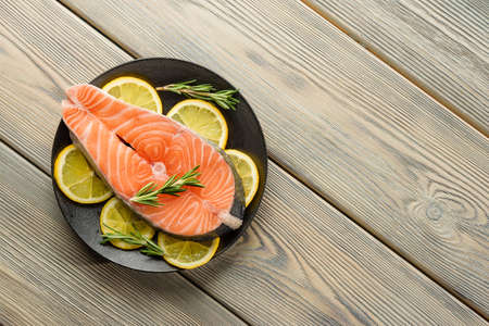 Salmon steak with spices and lemon on a wooden table background with copy space.の写真素材