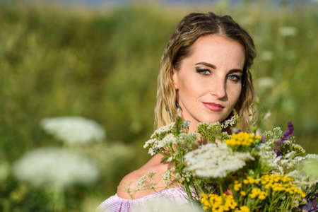 Portrait of a girl with a bouquet of wild flowers close-up.の写真素材