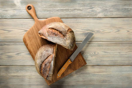 cutting board with a cut loaf of bread. Homemade bread cut in half on a wooden table with copy...