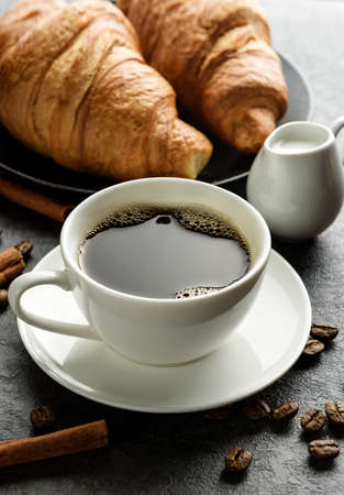 Close-up coffee cup with croissants and coffee beans.の写真素材
