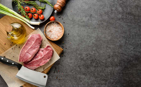 Marbled beef steaks and ingredients for cooking on a dark surface with a copy space.の写真素材