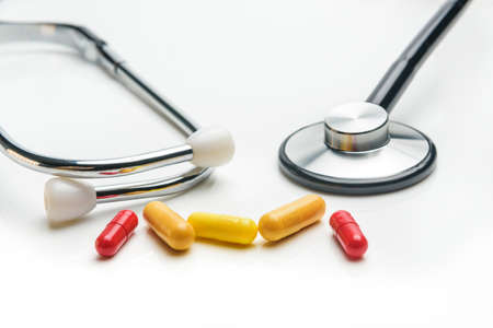 stethoscope and several capsules with medicine close-up on a white background with selective focus.の写真素材