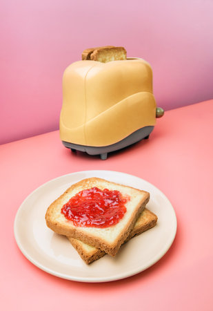 Dish with toast spread with jam and a toaster on a pink background. traditional breakfast concept.