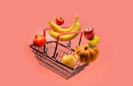 Grocery basket and fruits and vegetables on a pink background with copy space.の写真素材