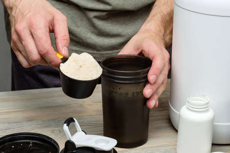 scoop with protein and sports shaker in male hands close-up.の写真素材