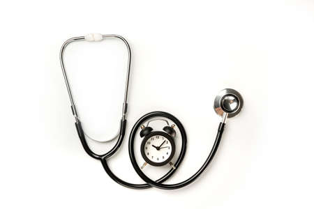 Stethoscope and alarm clock isolated on white background. The need to pass a medical examination on time.の写真素材