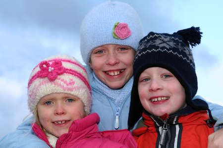 Happy children in winter outfit  on a blue sky background.